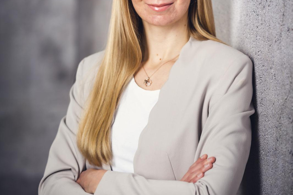 Carolin Christoph lächelt selbstbewusst vor einer grauen Wand. | © Florian Steiniger